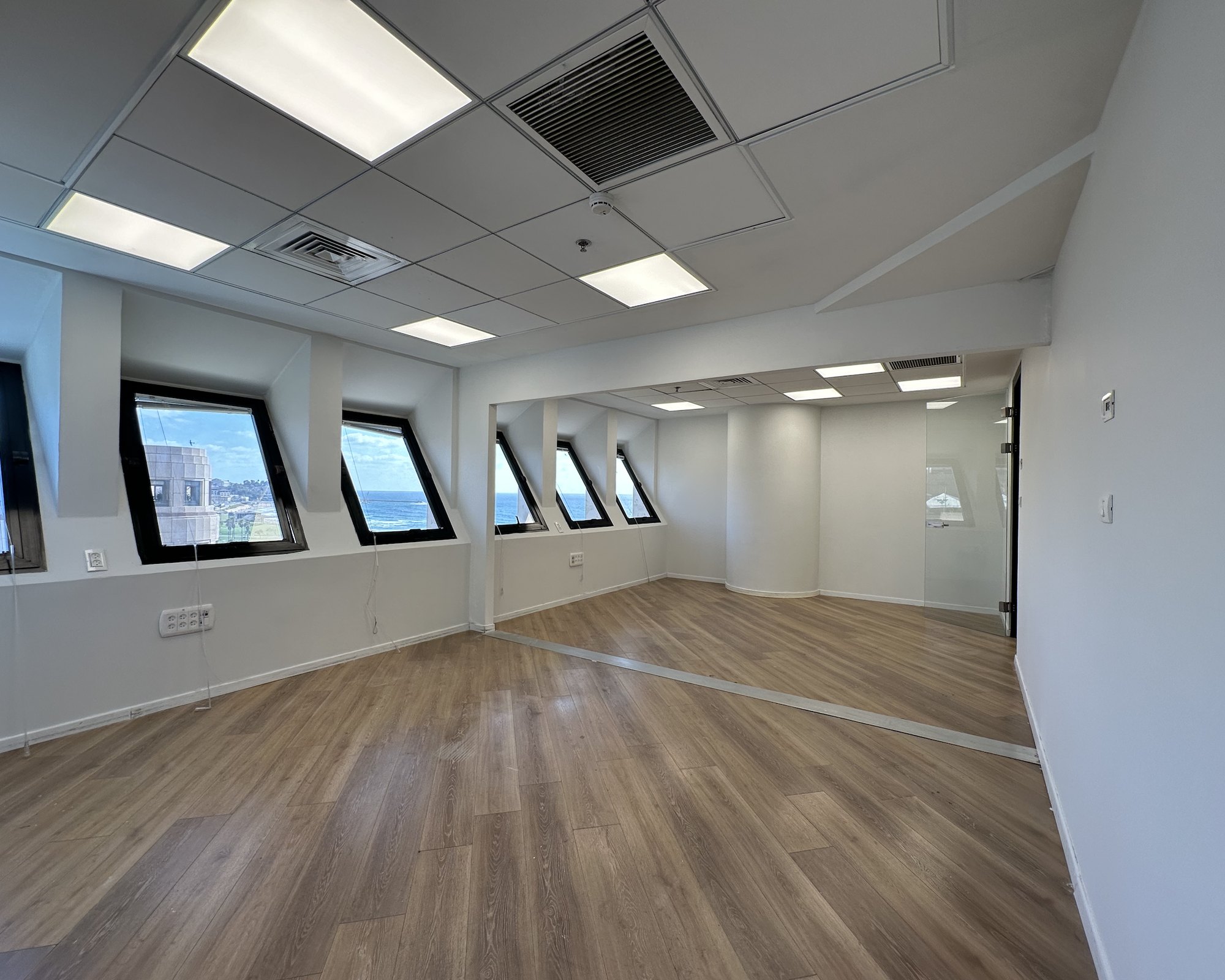 Empty floorplate with angled sea-view windows and a glass partition